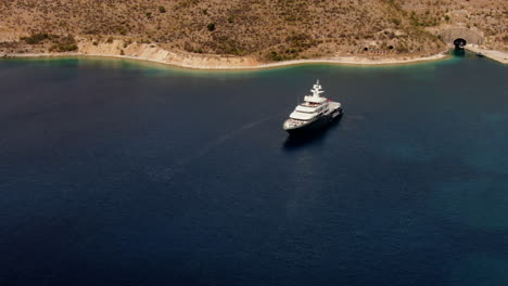 Circular-aerial-shot-on-a-luxurious-yacht-located-near-the-castle-of-Porto-Palermo-in-Albania