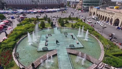 Eine-Luftaufnahme-Der-Stadt-Erbil-Mit-Der-Alten-Zitadelle-Von-Erbil-Und-Dem-Garten-Gegenüber-Dem-Schloss-Mit-Wasserfontänen-Und-Dem-Beliebten-Markt-1