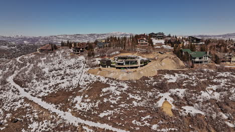 Park-City-Utah-Aerial-v17-low-level-drone-flyover-under-construction-hilltop-mansion-and-surrounding-luxurious-vacation-homes-against-clear-blue-sky---Shot-with-Mavic-3-Cine---February-2022