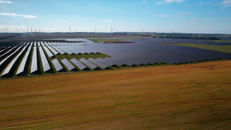 Solar-panel-rows-in-green-energy-production-facility,-aerial-pedestal-down