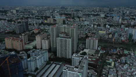 Saigon-or-Ho-Chi-Minh-City,-Vietnam-aerial-fly-in-to-urban-view-of-large-apartment-buildings-on-very-dark-stormy-evening