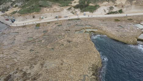 Top-aerial-view-of-chequerboard-of-rock-cut-saltpans-in-the-island-of-Gozo,-Malta