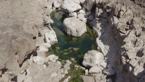 Drohnenaufnahme-Von-Oben-Nach-Unten-Von-Verschwindenden-Flussgewässern-In-Einem-Felsigen-Flussbett-Auf-Der-Insel-Sokotra