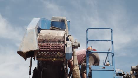 Detail-shot-of-a-Destemming-part-of-a-Grape-Harvester-in-Spain-being-Fixed-by-a-Worker-in-Slow-Motion-60fps