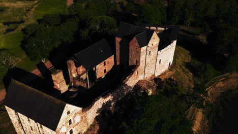 Aerial-view-overlooking-inside-the-Kastelholma-castle,-golden-hour-in-the-Aland-islands,-Finland---reverse,-drone-shot