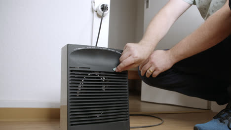 A-man-plugs-in-an-electric-fan-heater-in-the-hallway