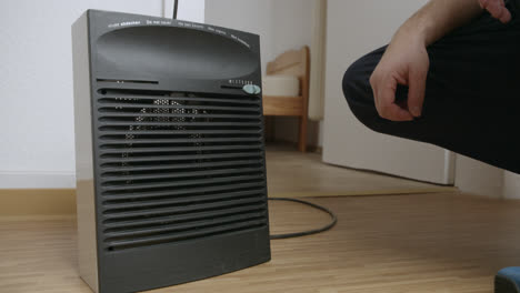 Close-up-of-a-hand-turning-up-the-temperature-of-an-electric-heater