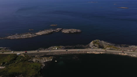 Aerial-view-following-traffic-on-the-Atlantic-ocean-road,-sunny,-summer-day,-in-Norway---pan,-drone-shot