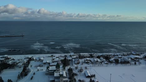 Drone-flying-over-coast-of-Japan-with-town-in-winter-snow