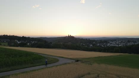 Low-Flyover-A-Wheat-Field-With-Braunfels-Castle-Silhouette-In-The-Background