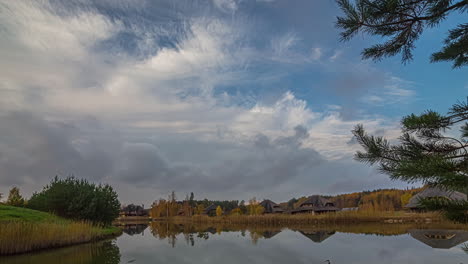 Timelapse-shot-of-cloud-movement-over-rows-of-cottages-by-the-side-of-a-lake-in-distance-during-evening-time