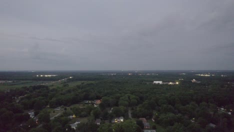 Aerial-drone-overview-shot-of-tree-tops-and-houses-during-evening-time-over-a-small-town