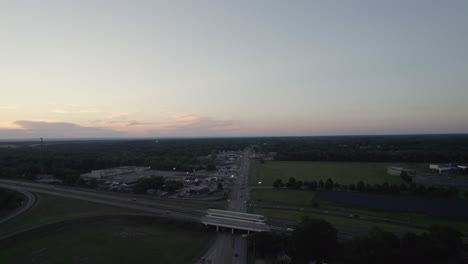 In-Der-Dämmerung-Erfasste-Eine-Drohne-Eine-Kleine-Stadt-In-Ohio-In-Der-Nähe-Einer-Autobahn,-Auf-Der-Ein-Auto-Auf-Und-Ab-Raste