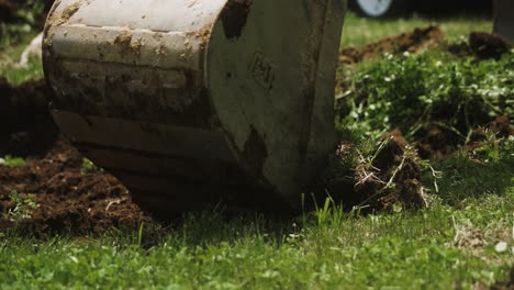 Excavator-bucket-cutting-through-grass-to-fresh-dirt