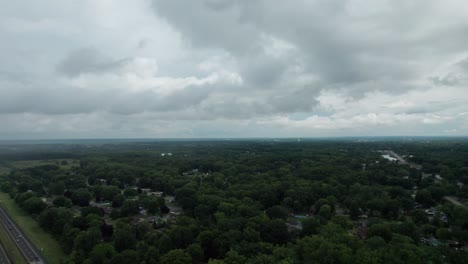 Drone-flying-toward-the-town-of-Ohio-which-is-surrounded-by-trees-from-a-great-height,-capturing-the-town-in-all-its-glory