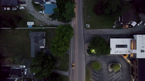 Aerial-top-shot-over-roads-in-the-residential-area-with-driving-cars-after-sunset