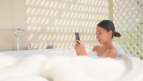 Close-up-of-a-pretty-young-woman-texting-from-a-bubble-bath
