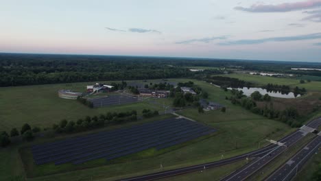 Drone-capture-the-busy-road-which-has-solar-panel-installed-in-the-side-and-nearby-town