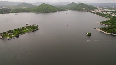 Aerial-dolly-in-revealing-speedboat-sailing-big-lake-in-Udaipur,-India