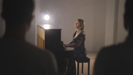 Pianista-Tocando-El-Piano-Vertical,-Realizando-Un-Concierto-íntimo-Frente-A-Una-Pequeña-Audiencia