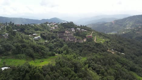 Drone-shot-of-buildings-surrounded-by-trees-and-forest-on-hills-in-Kohima,-Nagaland-India