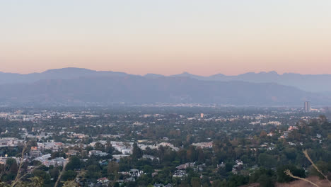 Puesta-De-Sol-Sobre-Una-Ciudad-Distante-En-Los-ángeles-Con-Colinas-En-El-Fondo,-California---Amplia