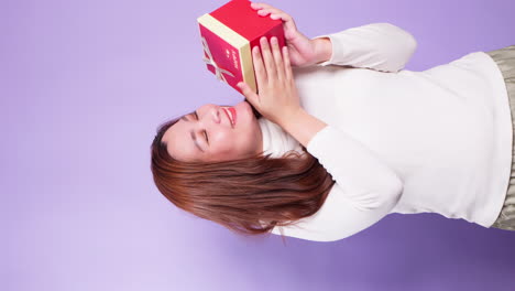 Vertical-Portrait-beautiful-of-Asian-happy-woman-holding-a-red-gift-box-standing-isolated-over-a-violet-background-1