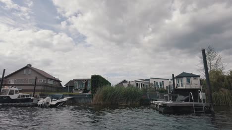 Häuser-Am-Flussufer-Mit-An-Docks-Angedockten-Privatbooten