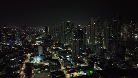 Panama-City-Aerial-V62-Flyover,-Calidonia-Viertel,-Schwenk-Nach-Oben,-Aufnahme-Des-Beleuchteten-Modernen-Stadtbilds-Der-Innenstadt-Mit-Hochhäusern-Am-Wasser-Bei-Nacht-–-Aufgenommen-Mit-Mavic-3-Cine-–-März-2022