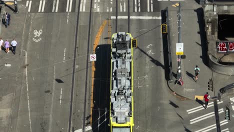 Top-down-aerial-shot-of-an-electric-street-car-traveling-through-Seattle's-busy-streets