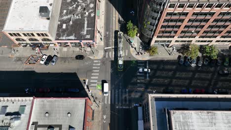 Top-down-aerial-shot-of-an-electric-street-car-traveling-through-Seattle's-industrial-streets