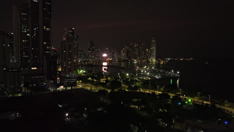 Panama-City-Aerial-v55-low-level-flyover-building-rooftop-at-calidonia-neighborhood-towards-affluent-punta-paitilla-peninsula-capturing-downtown-night-cityscape---Shot-with-Mavic-3-Cine---March-2022