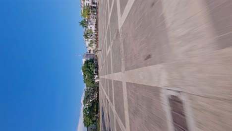 Fpv-flight-over-famous-Plaza-Espana-in-Santo-Domingo-Town-during-blue-sky-with-statue