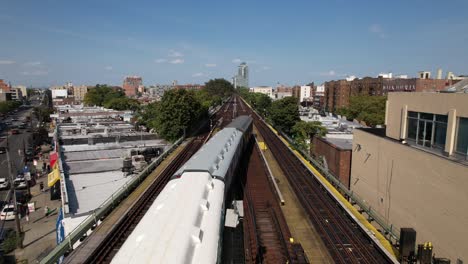 An-aerial-view-of-elevated-train-tracks-with-three-vintage-train-cars-travelling-away-from-the-camera-on-a-sunny-day