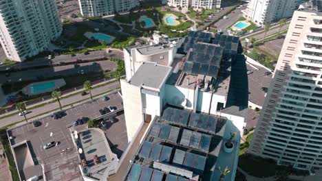 Aerial-orbit-of-several-solar-panels-on-the-rooftop-of-coastal-luxury-building