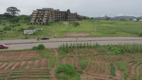 AERIAL---Abandoned-hotel-building-and-Lamingo-Dam,-Jos-Plateau,-Nigeria,-descending