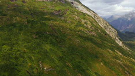 Aerial-view-of-cloud-shadows-moving-over-a-mossy-mountain-wall-in-sunny-Norway