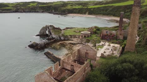 Aerial-view-exploring-deserted-remains-of-Porth-Wen-industrial-brickwork-factory-on-eroded-Anglesey-coastline