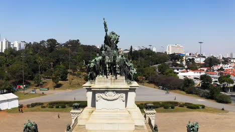 Camera-flying-down-and-away-from-the-Independence-Monument-in-the-Independence-Park-with-the-Ipiranga-Museum-in-the-background-of-the-scene