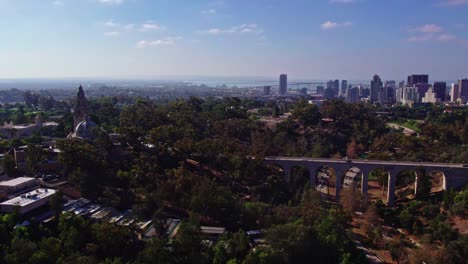 Aerial-Panoramic-View-of-above-Balboa-Park-Area-District-of-San-Diego-California,-Urban-Bridge-Streets-Roads-and-Buildings-on-Top-of-Green-Hill-Park,-Downtown-Cityscape-with-Coronado-bridge-in-Horizon
