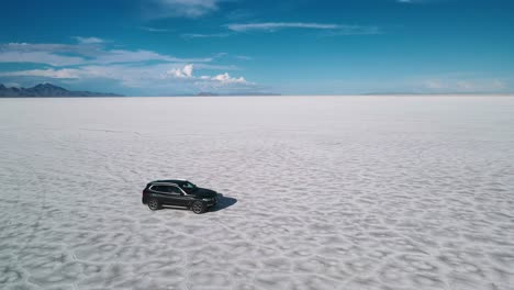 Cinematic-video-of-a-drone-tracking-a-car-from-the-side-on-a-remote-are-like-desert-at-high-speed,-bonnesville-salt-flats-utah,-usa-4k-aerial-clip