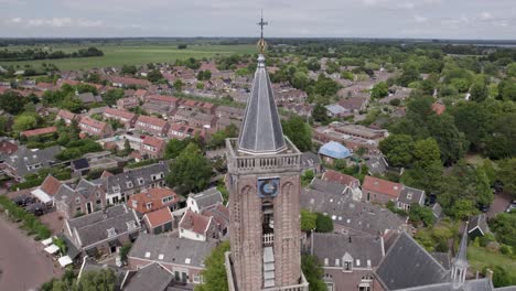 Aerial-view-of-a-church-tower-in-a-Dutch-village,-a-clock-on-a-church-tower,-religious-building