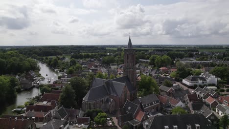 Circling-aerial-view-of-a-church-and-tower-in-a-Dutch-village-Loenen,-Netherlands