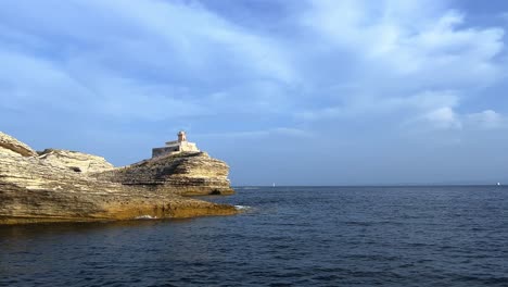 Madonnetta-Leuchtturm-Thront-Auf-Einer-Klippe-Entlang-Der-Südküste-Korsikas-In-Frankreich,-Gesehen-Vom-Segelboot-1