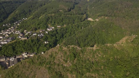 Vuelo-Aéreo-Sobre-Una-Montaña-Que-Revela-Una-Gran-Cantidad-De-Casas-Construidas-En-El-Valle-De-Cochem,-Alemania