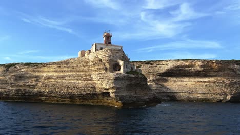 Incredible-low-angle-view-of-famous-Madonnetta-lighthouse-perched-on-cliff-in-Southern-Corsica-island-seen-from-tour-boat