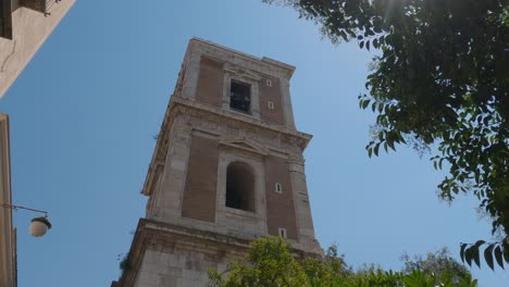 Look-up-at-the-bell-tower-of-Santa-Chiara-Church-on-a-sunny-blue-sky-day,-Naples,-Italy