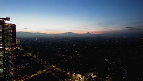 Aerial-view-rising-over-the-illuminated-Chapultepec-Avenue,-over-the-Roma-Nte-district,-dusk-in-Mexico-city