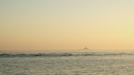 Blick-Auf-Einen-Leuchtturm-Von-Einem-Boot-Mitten-Im-Meer-Bei-Sonnenuntergang