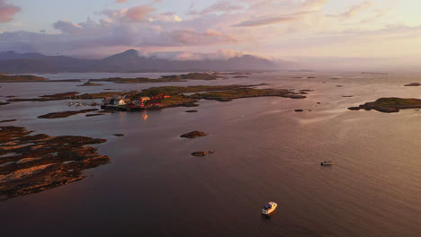 Aerial-view-over-fishing-boats-towards-the-Atlanterhavsveien,-dramatic-sunset-in-Norway---rising,-drone-shot